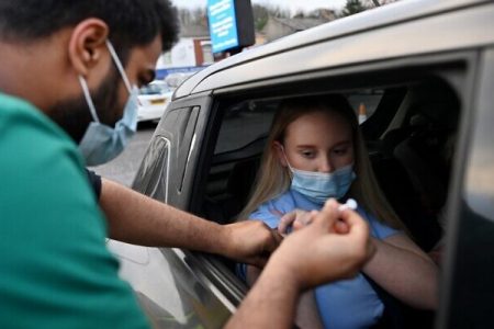 A member of the public receives a Covid-19 vaccine at a drive-through NHS (National Health Service) vaccination centre outside Ewood Park, Blackburn Rovers Football Club in Blackburn in north-west England on January 17, 2022, as the Omicron coronavirus variant spreads in the country. (Photo by Paul ELLIS / AFP)