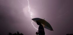 A pedestrian walks with an umbrella as lightning strikes during an evening thunderstorm in Jammu on May 14, 2015. AFP PHOTO / RAKESH BAKSHI (Photo by rakesh bakshi / AFP)