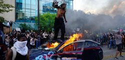 0_A-man-stands-on-top-of-a-burning-police-car-during-a-protest