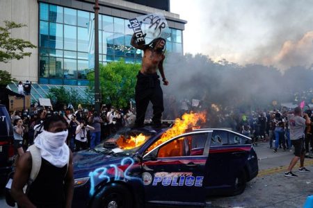 0_A-man-stands-on-top-of-a-burning-police-car-during-a-protest