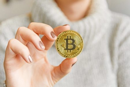 106820278-1609972654383-hand-holding-a-bitcoin-in-front-of-a-computer-screen-with-a-dark-graph-blockchain-mining-bitcoin_t20_pRrrjP