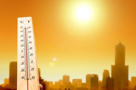 heat wave in the city and hand showing thermometer for high temperature