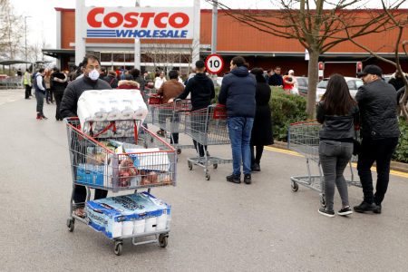 FILE PHOTO: A masked customer leaves with shopping as other customers queue to enter a Costco Wholesalers in Chingford, Britain March 15, 2020. REUTERS/John Sibley