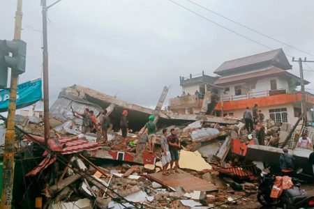 Residents inspect an earthquake-damaged buildings in Mamuju, West Sulawesi, Indonesia, Friday, Jan. 15, 2021. A strong inland and shallow earthquake hit eastern Indonesia early Friday causing people to panic in parts of the country???s Sulawesi island and run to higher ground. (AP Photo/Rudy Akdyaksyah)