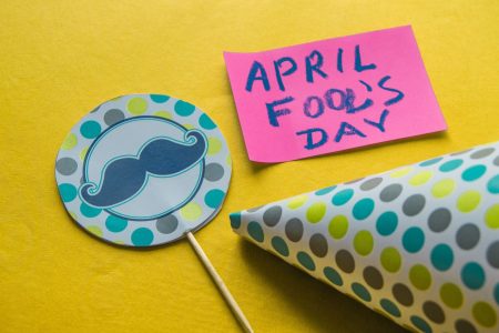 Cap, topper with a mustache and notes with the phrase April fool's day on a yellow background.