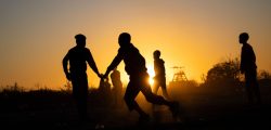 A silhouette shot of Boys Playing soccer at sunset time