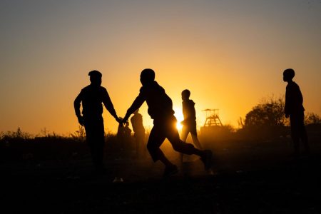 A silhouette shot of Boys Playing soccer at sunset time