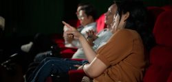 Asian mother and daughter watching movie in cinema. Family time concept.