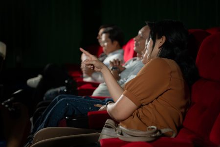 Asian mother and daughter watching movie in cinema. Family time concept.