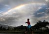 A-young-girl-plays-as-a-rainbow-is-seen-on-the-monsoon-sky-in-Kathmandu.
