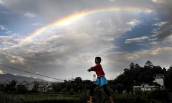 A-young-girl-plays-as-a-rainbow-is-seen-on-the-monsoon-sky-in-Kathmandu.