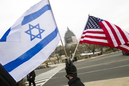 A pro-Israel demonstrators waves flags, toward the Capitol in Washington, Tuesday, March 3, 2015, as Israeli Prime Minister Benjamin Netanyahu addressed a joint meeting of Congress. In a speech that stirred political intrigue in two countries, Netanyahu told Congress that negotiations underway between Iran and the U.S. would "all but guarantee" that Tehran will get nuclear weapons, a step that the world must avoid at all costs. (AP Photo/Cliff Owen)