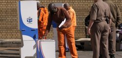 An officer watches on as an inmate inserts his ballot paper into the ballot box at the polling station at Kgoši Mampuru Correctional Facility in Pretoria, South Africa, Wednesday, May 29, 2024. South Africans voted Wednesday at schools, community centers, and in large white tents set up in open fields in an election seen as their country’s most important in 30 years. It could put the young democracy in unknown territory.(AP Photo/Themba Hadebe)