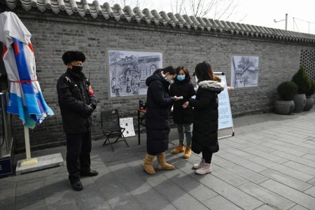 A woman uses a thermometer to check a woman?s temperature at the entrance of a business street being closed due to coronavirus epidemic in Beijing on February 21, 2020. - The death toll in China from the coronavirus epidemic rose to 2,233 on February 21 after 115 more people died in Hubei province, the hard-hit epicentre of the outbreak. (Photo by STR / AFP)