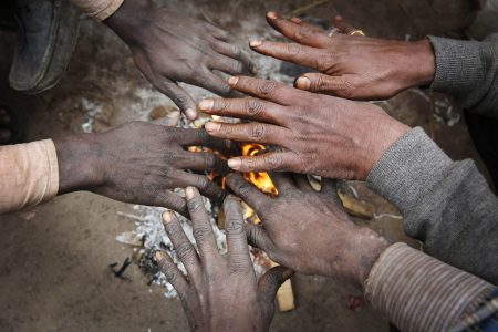 Indian men warm their hands near a bonfire on a cold and foggy morning in Allahabad, India, Sunday, Dec. 21, 2014. Intense cold wave continues unabated in north India with fog disrupting traffic movements at several places. (AP Photo/Rajesh Kumar Singh)