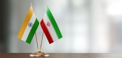 Indian and Iranian flag pair on desk over defocused background. Horizontal composition with copy space and selective focus.