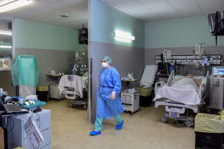 A medical worker wearing a protective mask and suit and a patient suffering from coronavirus disease (COVID-19) are seen in an intensive care unit at the Oglio Po hospital in Cremona, Italy March 19, 2020. REUTERS/Flavio Lo Scalzo