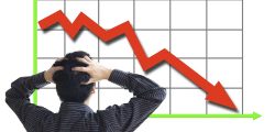 Frustrated business man looking at the falling graph of a stock market struck in financial crisis