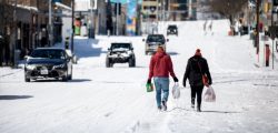 AUSTIN, TX - FEBRUARY 15: People carry groceries from a local gas station on February 15, 2021 in Austin, Texas. Winter storm Uri has brought historic cold weather to Texas, causing traffic delays and power outages, and storms have swept across 26 states with a mix of freezing temperatures and precipitation. (Photo by Montinique Monroe/Getty Images)