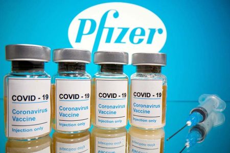 FILE - Vials with a sticker reading, "COVID-19 / Coronavirus vaccine / Injection only" and a medical syringe are seen in front of a displayed Pfizer logo in this illustration taken on October 31, 2020. Illustration: Reuters via Dado Ruvic