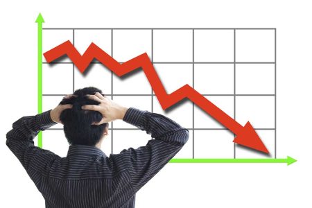 Frustrated business man looking at the falling graph of a stock market struck in financial crisis