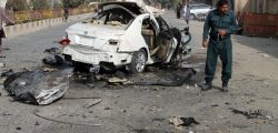 An Afghan policeman investigates a damaged car following a sticky bomb attack in Helmand province, southern Afghanistan, Thursday, Nov. 12, 2020. A bomb attached to the vehicle of a radio journalist in southern Afghanistan exploded early Thursday, killing him, a provincial official said. (AP Photo/Abdul Khaliq)