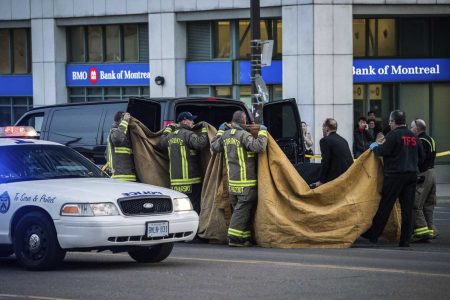Officials carry a body into a vehicle after a van mounted a sidewalk crashing into pedestrians in Toronto on Monday, April 23, 2018. The rented van jumped onto the crowded sidewalk Monday, killing and injuring people before the driver fled and was quickly arrested in a confrontation with police, Canadian authorities said. (Aaron Vincent Elkaim/The Canadian Press via AP)