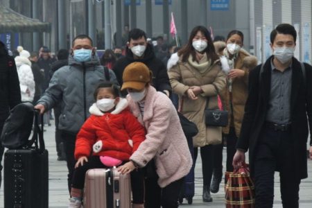 YICHANG, CHINA - JANUARY 21 2020: Travelers wearing protective masks walk outside a railway station in Yichang in central China's Hubei province Tuesday, Jan. 21, 2020. China has stepped up the measures to control the spread of the new coronavirus that has infected hundreds of people in China.