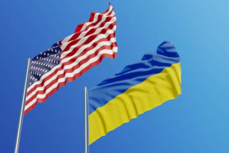 American and Ukrainian flags are waving with wind over  blue sky. Low angle view. Dispute and conflict concept. Horizontal composition with copy space.