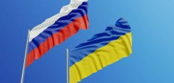 Russian and Ukrainian flags are waving with wind over  blue sky. Low angle view. Dispute and conflict concept. Horizontal composition with copy space.
