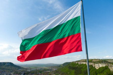 Bulgaria National Flag Waving on pole against sunny blue sky background.