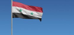 Flag of Syria in front of a clear blue sky