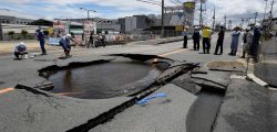 Workers stand by a partially collapsed road following an earthquake in Takatsuki, north of Osaka prefecture on June 18, 2018. 
At least two people, including a child, were killed on June 18, after a strong quake rocked the second city of Osaka during the morning rush hour, Japan's government said. / AFP PHOTO / JIJI PRESS / STR / Japan OUT