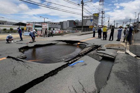 Workers stand by a partially collapsed road following an earthquake in Takatsuki, north of Osaka prefecture on June 18, 2018. 
At least two people, including a child, were killed on June 18, after a strong quake rocked the second city of Osaka during the morning rush hour, Japan's government said. / AFP PHOTO / JIJI PRESS / STR / Japan OUT