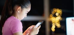 Young people and youth problems. Preteen girl left alone at home, sends text messages with phone to friends. Concept of potential victim of cyber bulling and absence of parental control