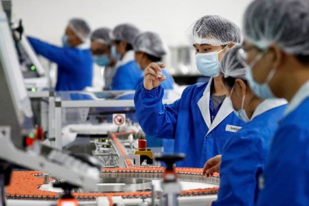 People work in the packaging facility of Chinese vaccine maker Sinovac Biotech, developing an experimental coronavirus disease (COVID-19) vaccine, during a government-organized media tour in Beijing, China, September 24, 2020. REUTERS/Thomas Peter - RC2X4J90605E