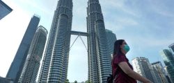 A woman wearing a face mask walks  in front of Twin Towers in Kuala Lumpur, Malaysia, Wednesday, March 18, 2020. For most people the new COVID-19 coronavirus causes only mild or moderate symptoms, but for some it can cause more severe illness. (AP Photo/Vincent Thian)