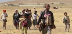 Displaced people from the minority Yazidi sect walk toward the Syrian border on the outskirts of Sinjar mountain on Monday. A U.S. assessment team says far fewer refugees are stranded on Mount Sinjar than previously though