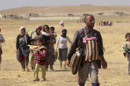 Displaced people from the minority Yazidi sect walk toward the Syrian border on the outskirts of Sinjar mountain on Monday. A U.S. assessment team says far fewer refugees are stranded on Mount Sinjar than previously though