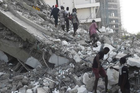 People walk to rescue workers from the rubble of a 21-storey building under construction that collapsed at Ikoyi district of Lagos, on November 1, 2021. - Several people have been trapped while unspecified number of people mostly construction workers were feared dead as a 21-storey building suddenly collapsed in the Ikoyi district of Lagos, Nigeria's commercial capital. (Photo by PIUS UTOMI EKPEI / AFP) (Photo by PIUS UTOMI EKPEI/AFP via Getty Images)