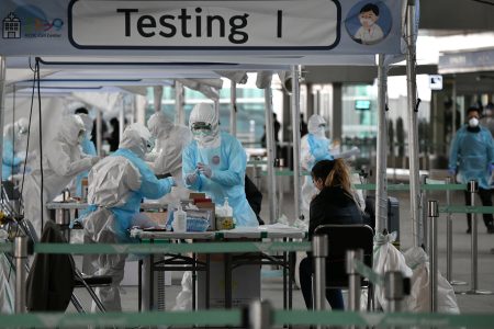 TOPSHOT - Medical staff wearing protective clothing take test samples for the COVID-19 coronavirus from a foreign passenger at a virus testing booth outside Incheon international airport, west of Seoul, on April 1, 2020. - The first charter flight arranged by South Korean government to evacuate its citizens from coronavirus-hit Italy returned home with 309 citizens on April 1, amid the worsening virus outbreak in the European country. (Photo by Jung Yeon-je / AFP) (Photo by JUNG YEON-JE/AFP via Getty Images)