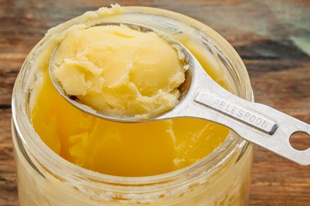 jar and measuring tablespoon of ghee - clarified butter
