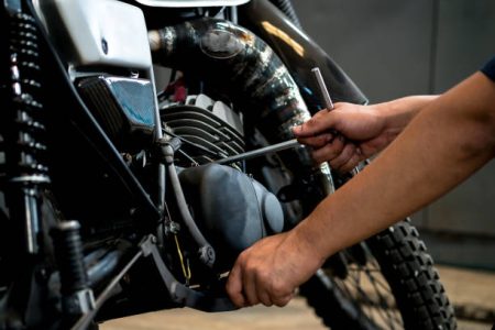 Image is Close up,People are repairing a motorcycle Use a wrench and a screwdriver to work.
